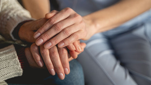 two people holding hands comforting each other