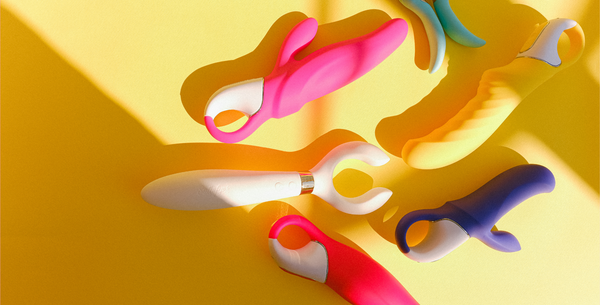 Collection of bright coloured sex toys on yellow background