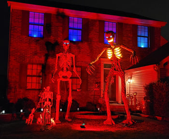 Employee, Alan B.'s house decorated as a haunted graveyard with skeletons lit up in red