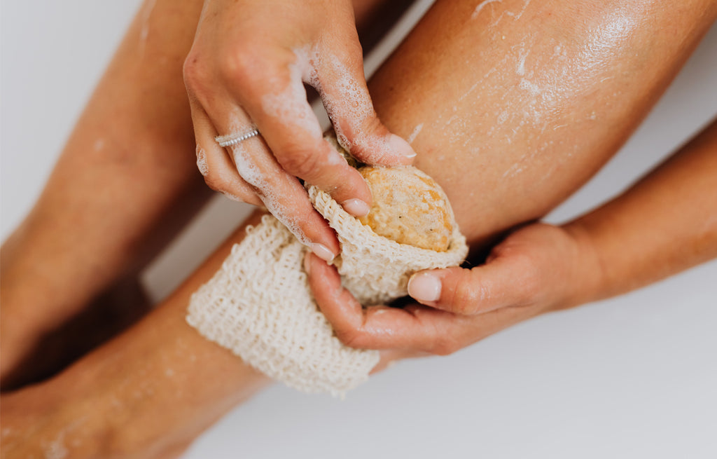 A close-up view of someone's feet submerged in a bath, with a gentle exfoliating scrub applied to remove dead skin cells.