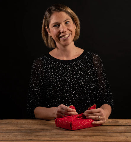 Jane from Furoshiki Wrap Company wrapping a gift with a festive red furoshiki