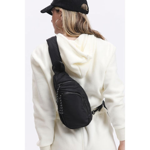 a woman in a cozy sweatsuit wearing a nylon neoprene sling backpack