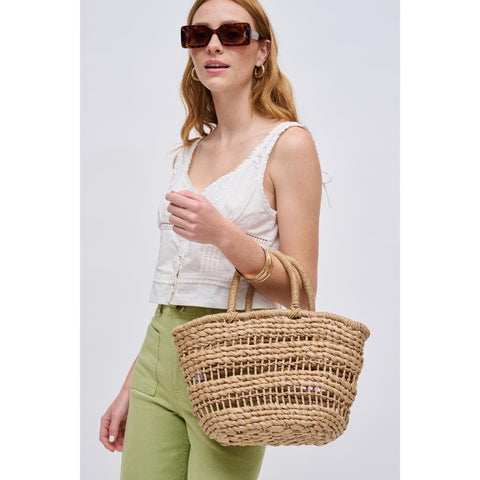 A woman carrying a straw tote for a quiet luxury look