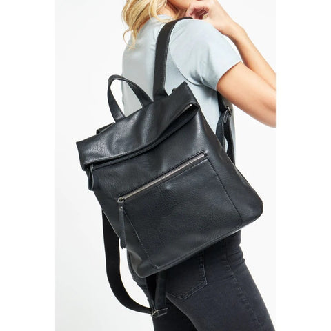 Woman in baby blue t-shirt and black jeans with black vegan leather backpack on her shoulder