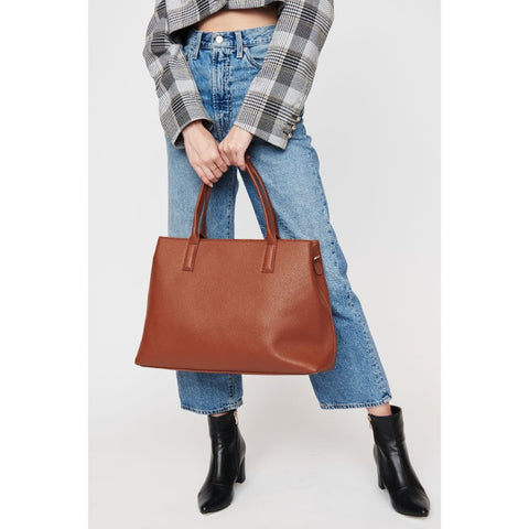 a woman in a blazer coat, jeans, and ankle boots holding a tan tote bag