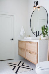 Bright white bathroom with a large circular mirror over the sink