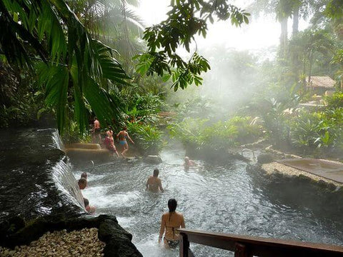 people swimming in a steaming pool in the jungle