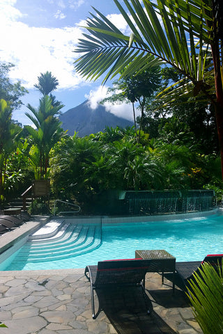 poolside with a volcano in the distance surrounded by jungle