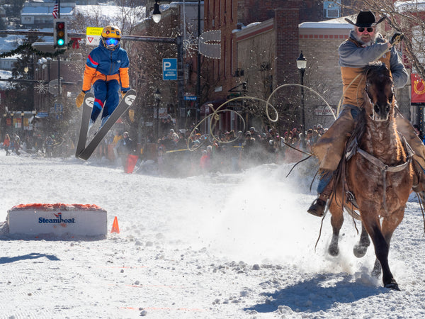 kid skijoring and jumping in winter jacket and pants in Steamboat Winter Carnival