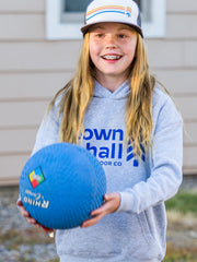 Charlotte holding a kickball in a Town Hall Logo Hoodie