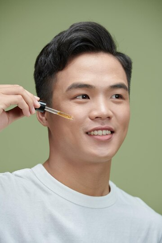 Young handsome Asian man applying serum on his face - Best Men Skin Care Malaysia Routine - beautyfoomall.com