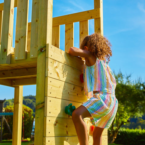 Child playing on wooden climbing frame climbing wall