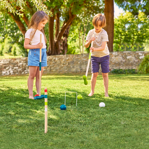 Children playing with wooden croquet game in garden