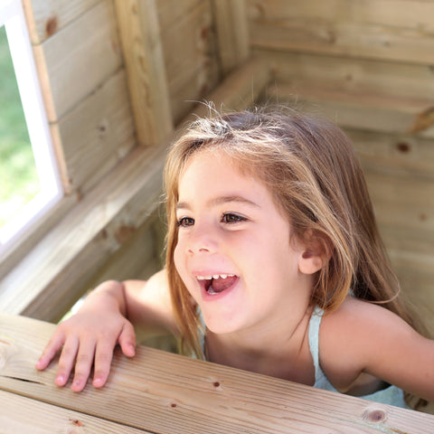 Child playing inside a two storey wooden playhouse
