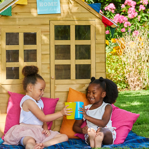 Children sitting in front of wooden playhouse