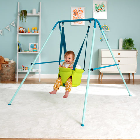 baby playing on a toddler swing set indoors