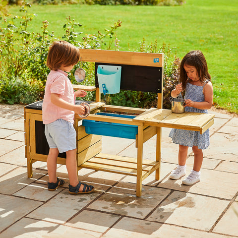 Two children playing with mud kitchen