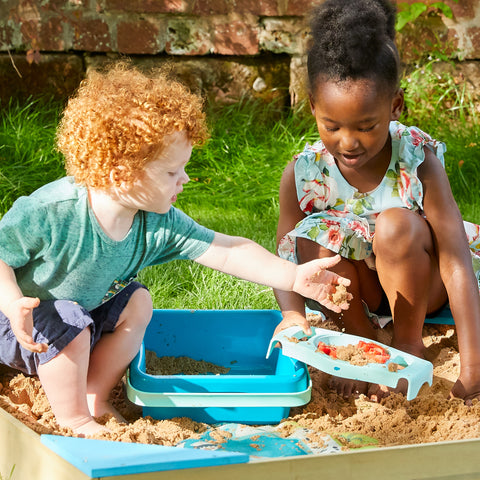 Children playing in sand pit with sand pit accessories