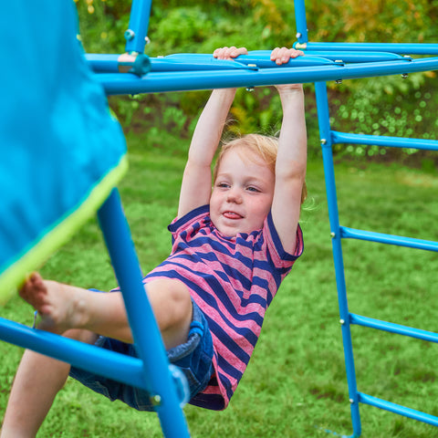 Child swinging on metal climbing frame monkey bars