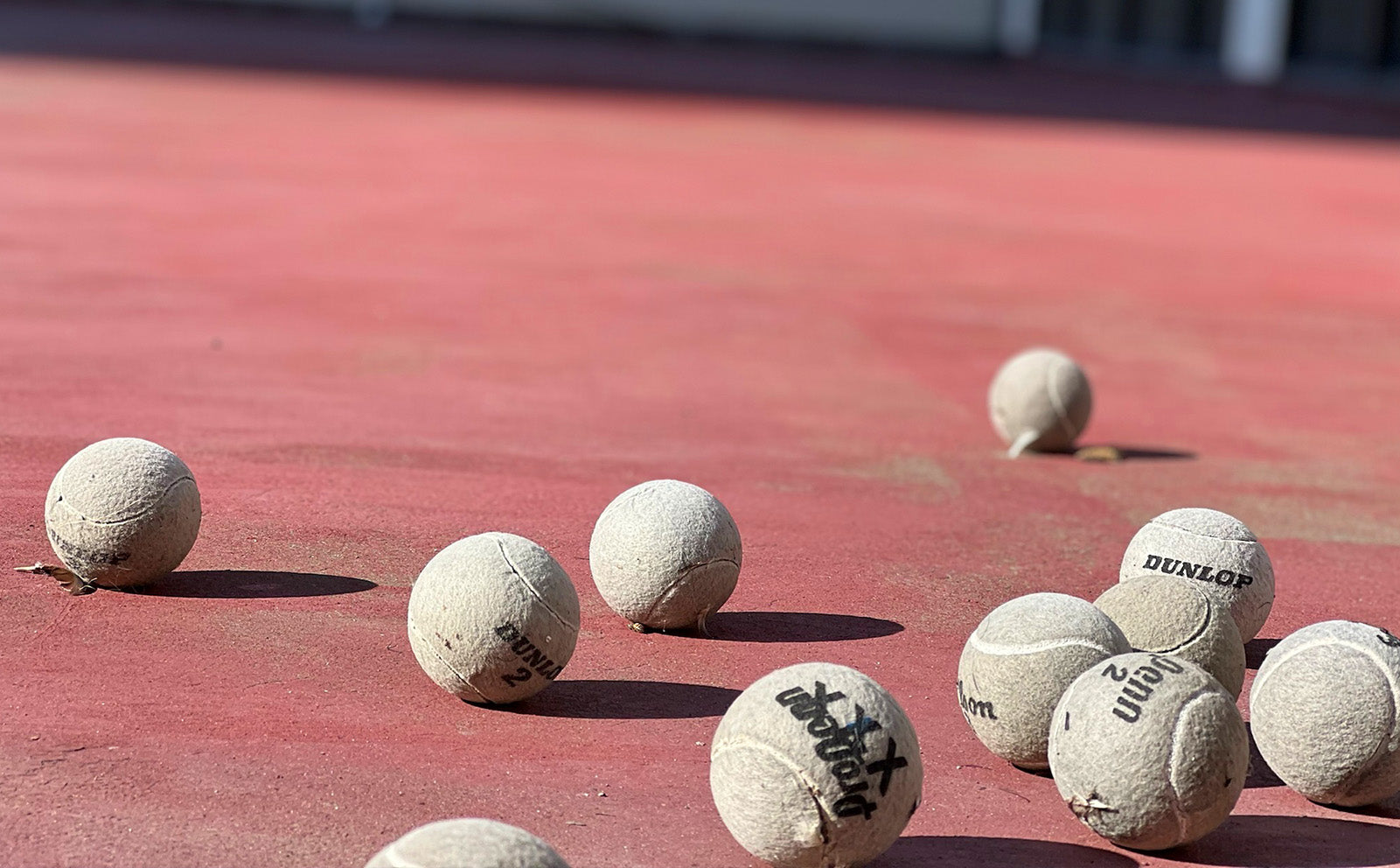 Dusty, grey tennis balls on a clay court