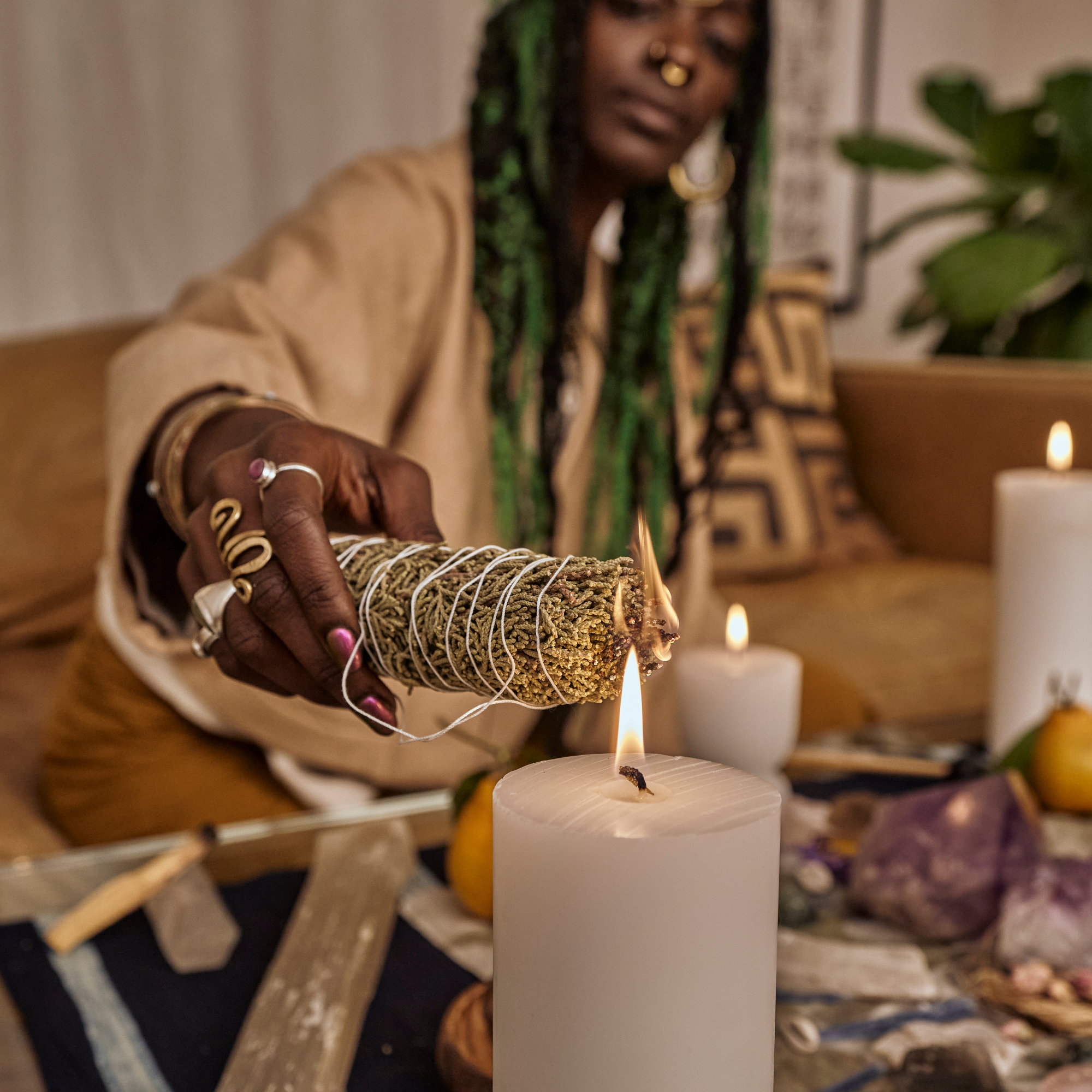 woman cleansing her space with sage sticks and candle