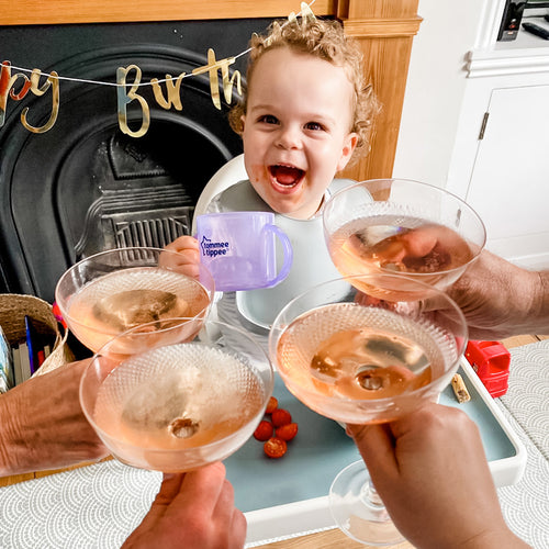 baby celebrating weaning with parents and doing cheers with drinks