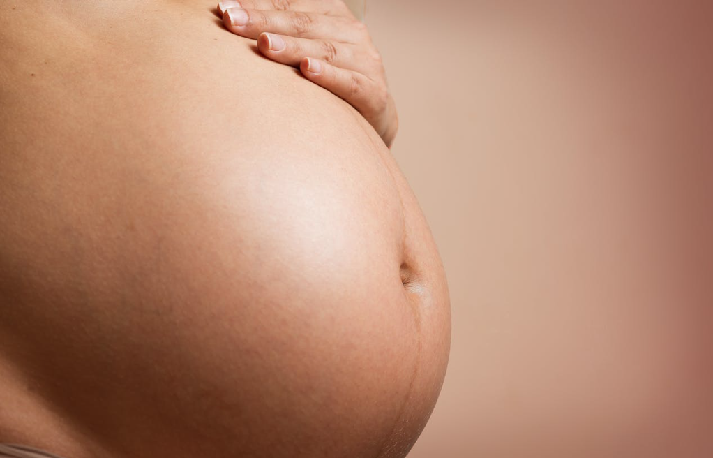 a pregnant woman’s hand on her baby bump