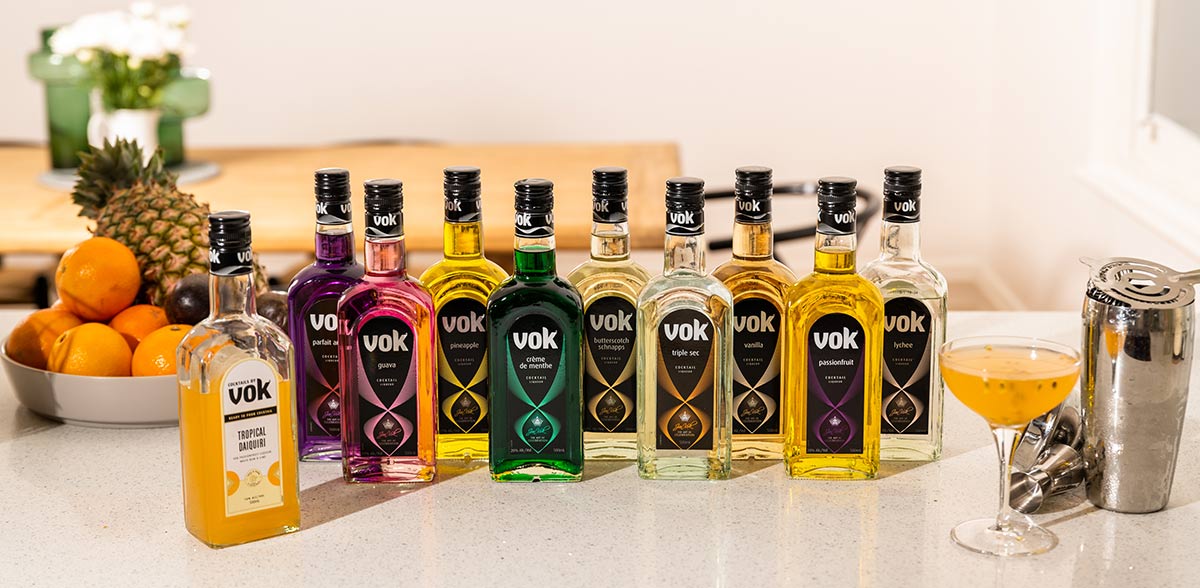 bottles of vok liqueurs lined up on a kitchen bech with a cocktail and shaker