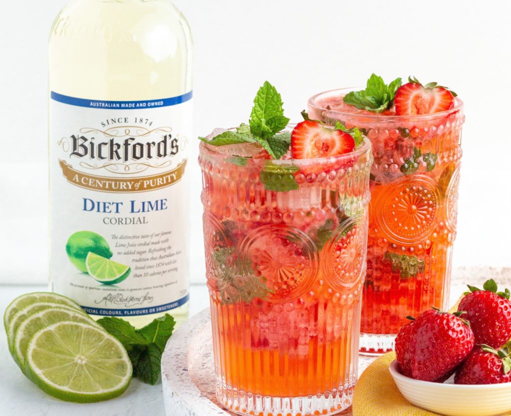 2 glasses of lime strawberry smash mocktails next to a bottle of Bickfords lime cordial