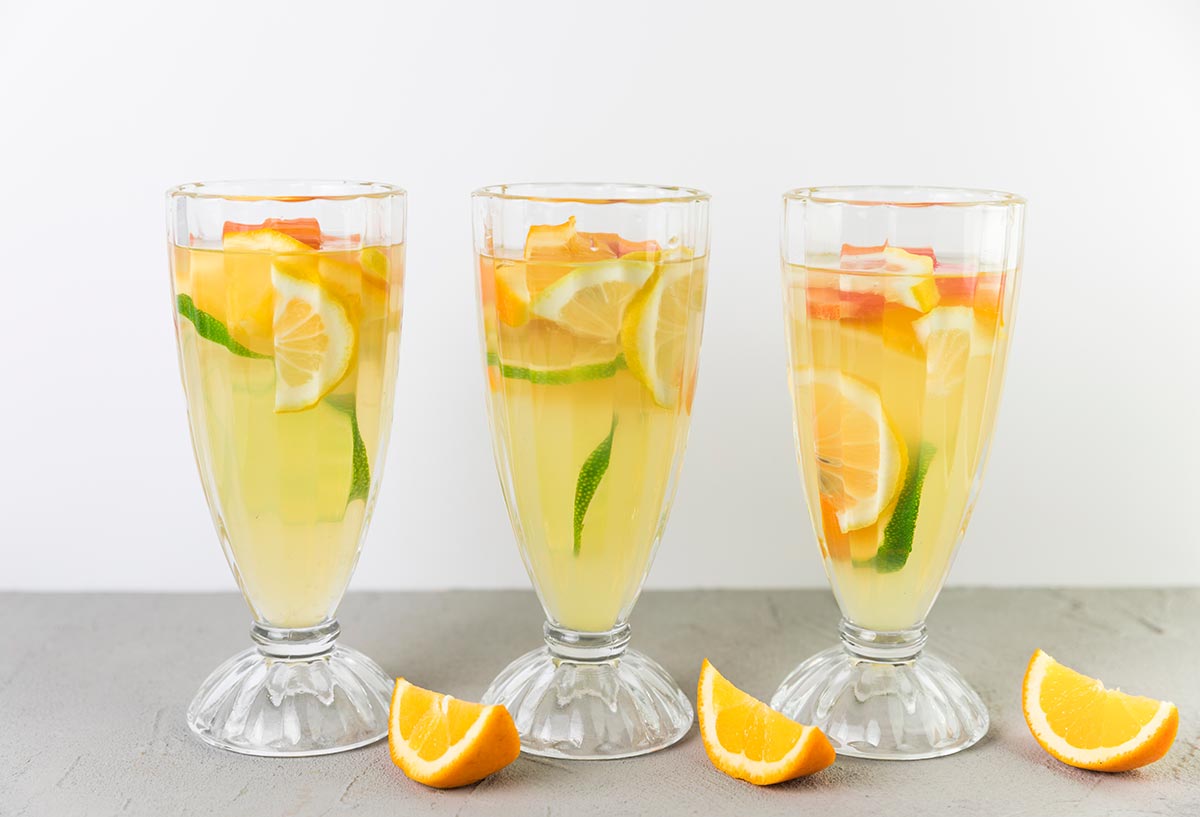 three citrus gin fizz cocktails with an orange wedge next to them