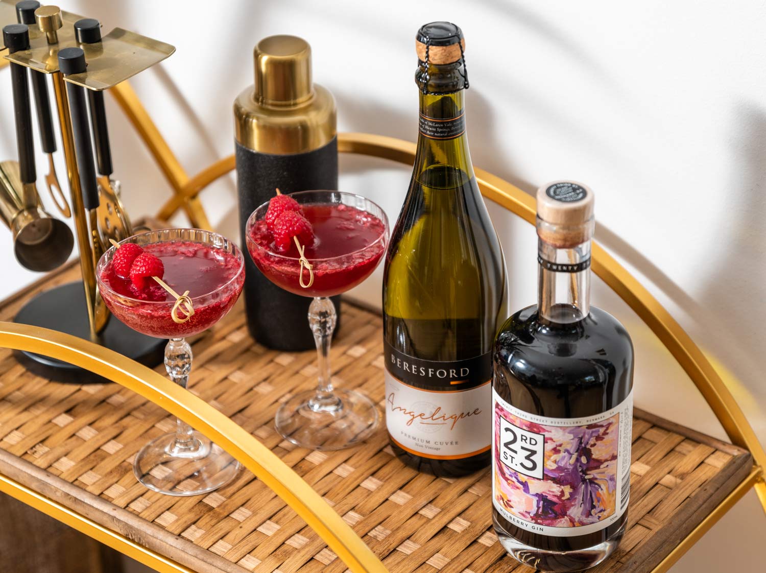 red cocktails on a bar cart with 23rd street mulberry gin bottle