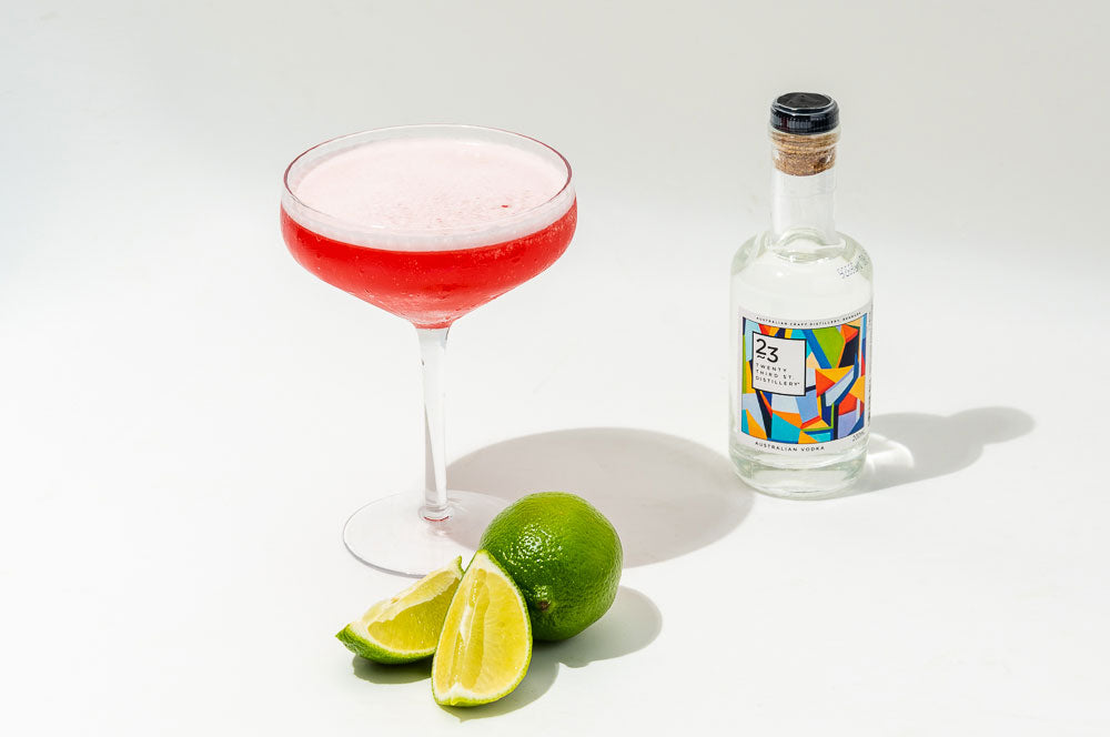 cosmopolitan cocktail with lime wedges and bottle of 23rd street Australian vodka