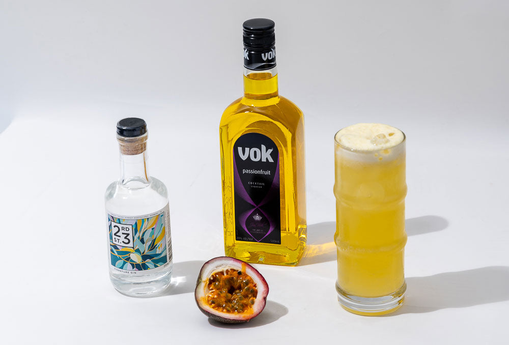 passion fruit collins cocktail in a glass with 23rd street vodka and vok passionfruit liqueur