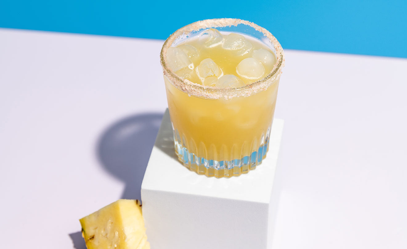 pineapple margarita on table with blue background