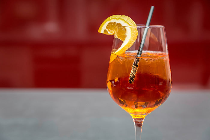 aperol spritz cocktail with a lemon wedge and a straw