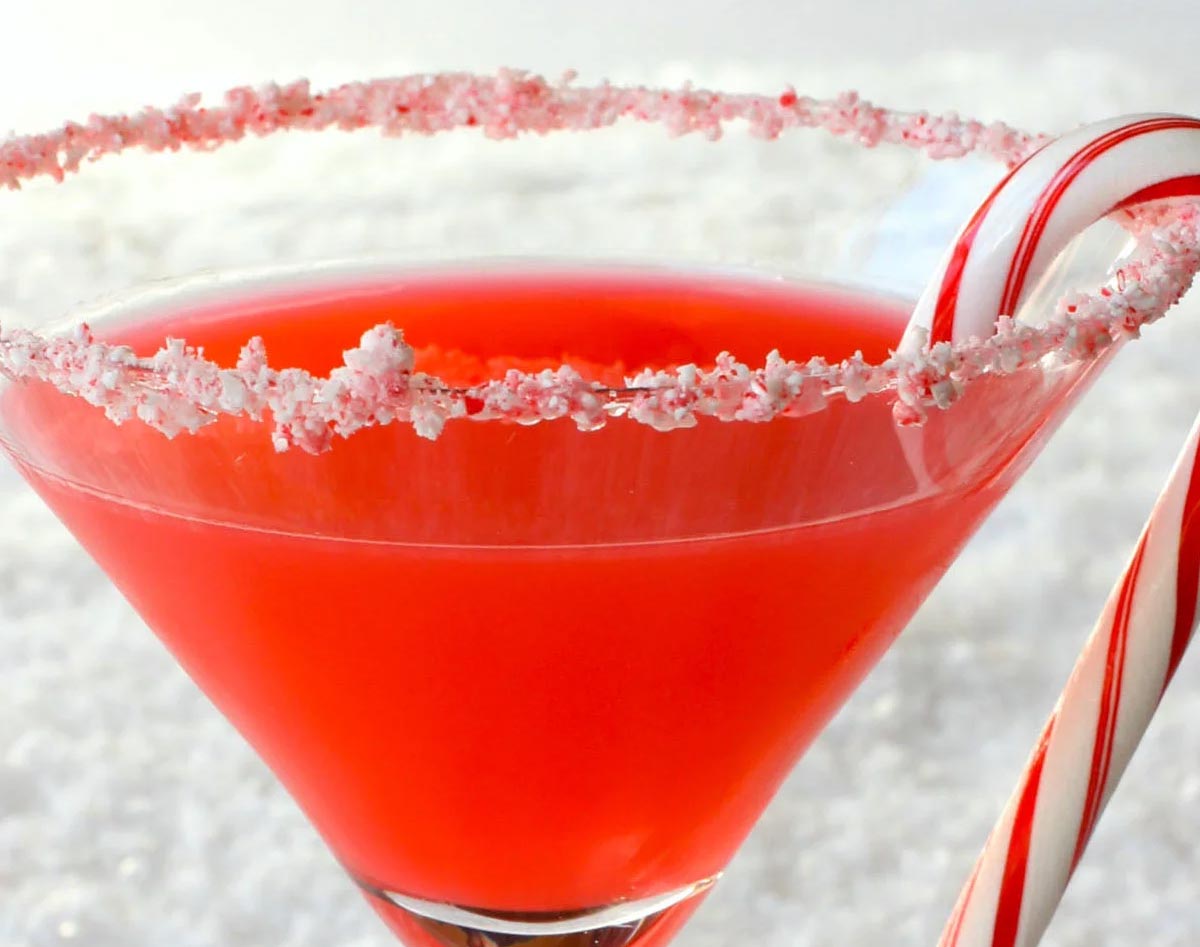 close up of candy cane martini with a candy cane hooked onto the side