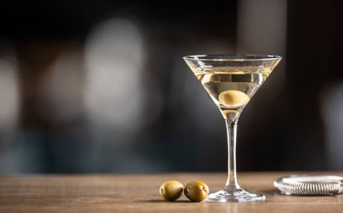 Classic Martini with an olive and two olives on the table beside the glass