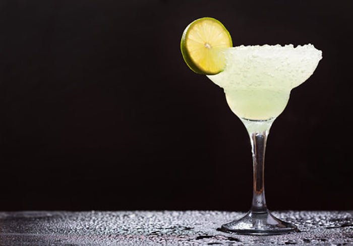 Margarita cocktail with a lime slice in front of a black background