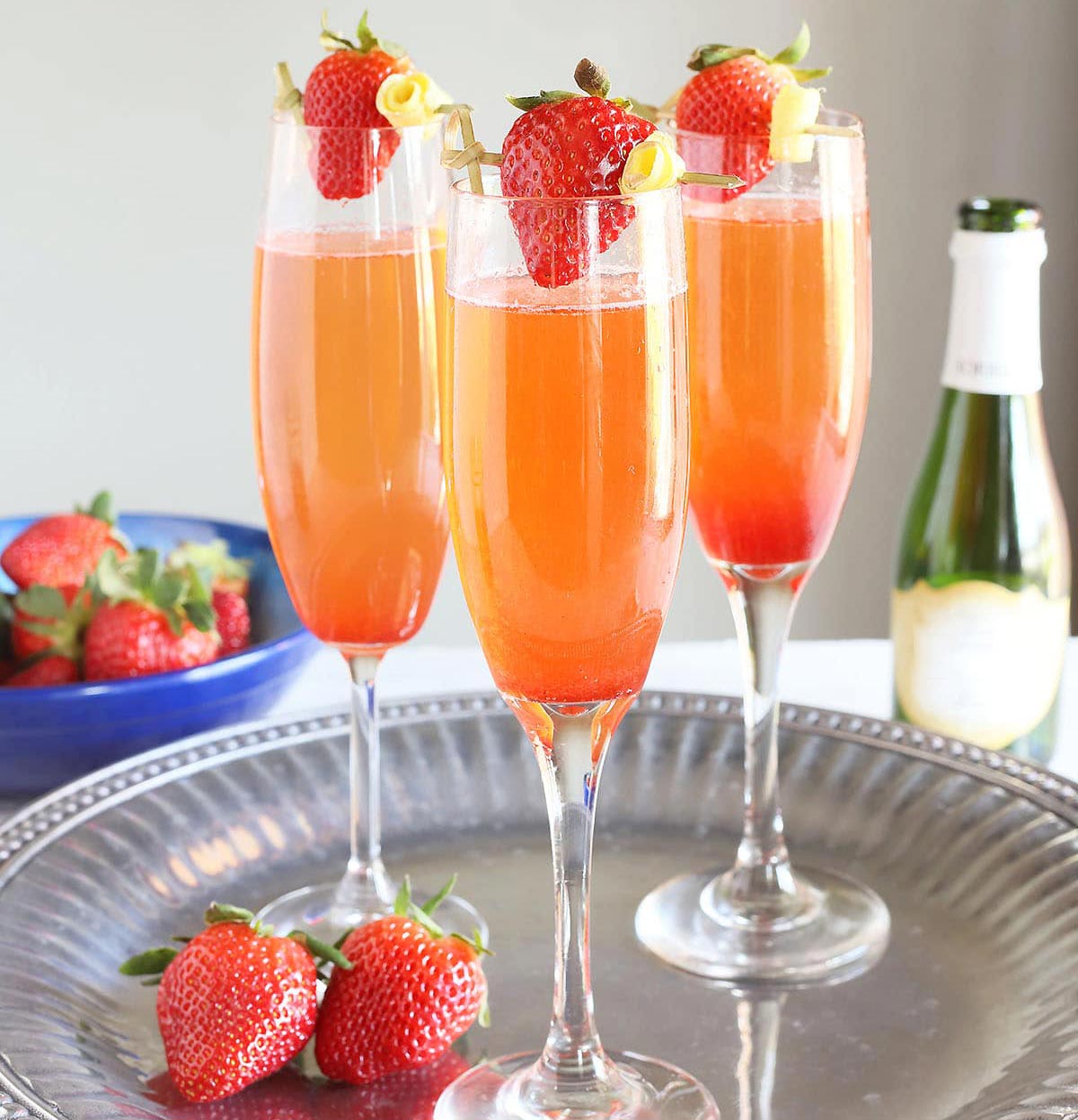 three glasses of strawberry champagne on a silver tray