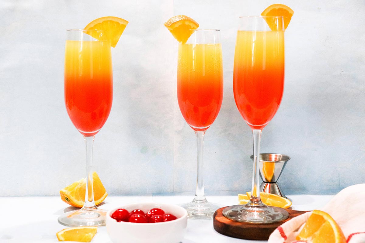three glasses of tequila sunrise mimosa's with orange garnish