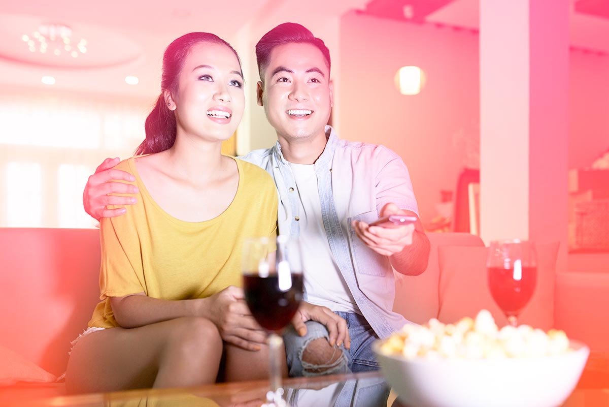 couple on couch enjoying a movie night with popcorn and wine