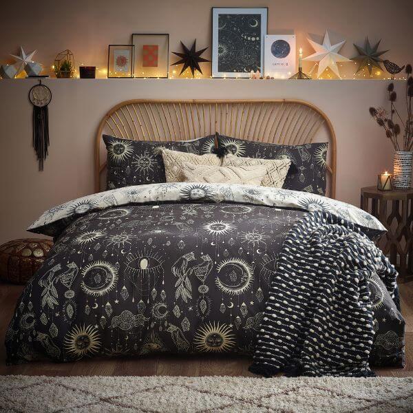 A black and cream duvet cover set with an abstract design of moons, starts and other night sky motifs.