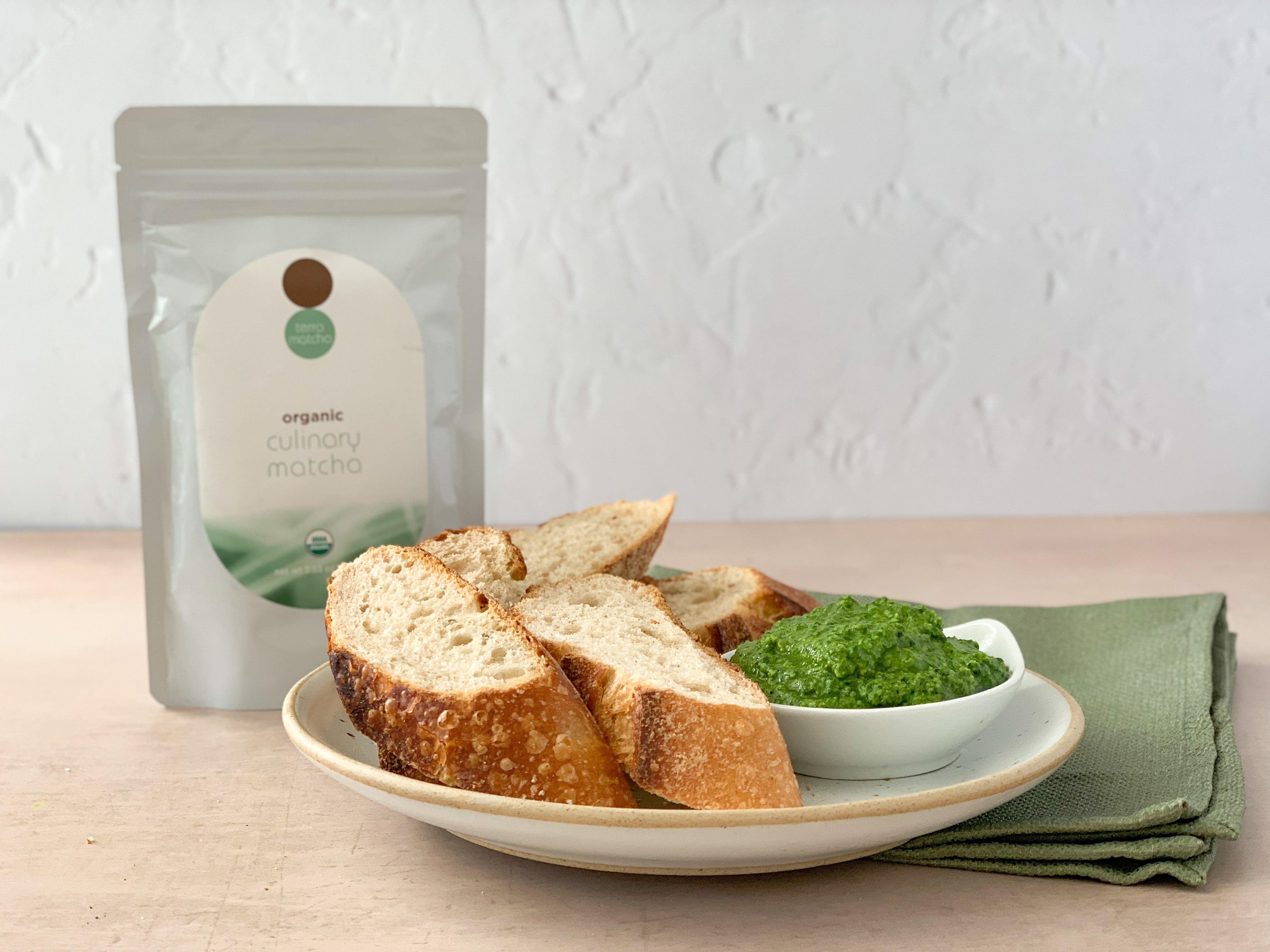 plate of bread with small bowl of matcha pesto and terra matcha culinary bag