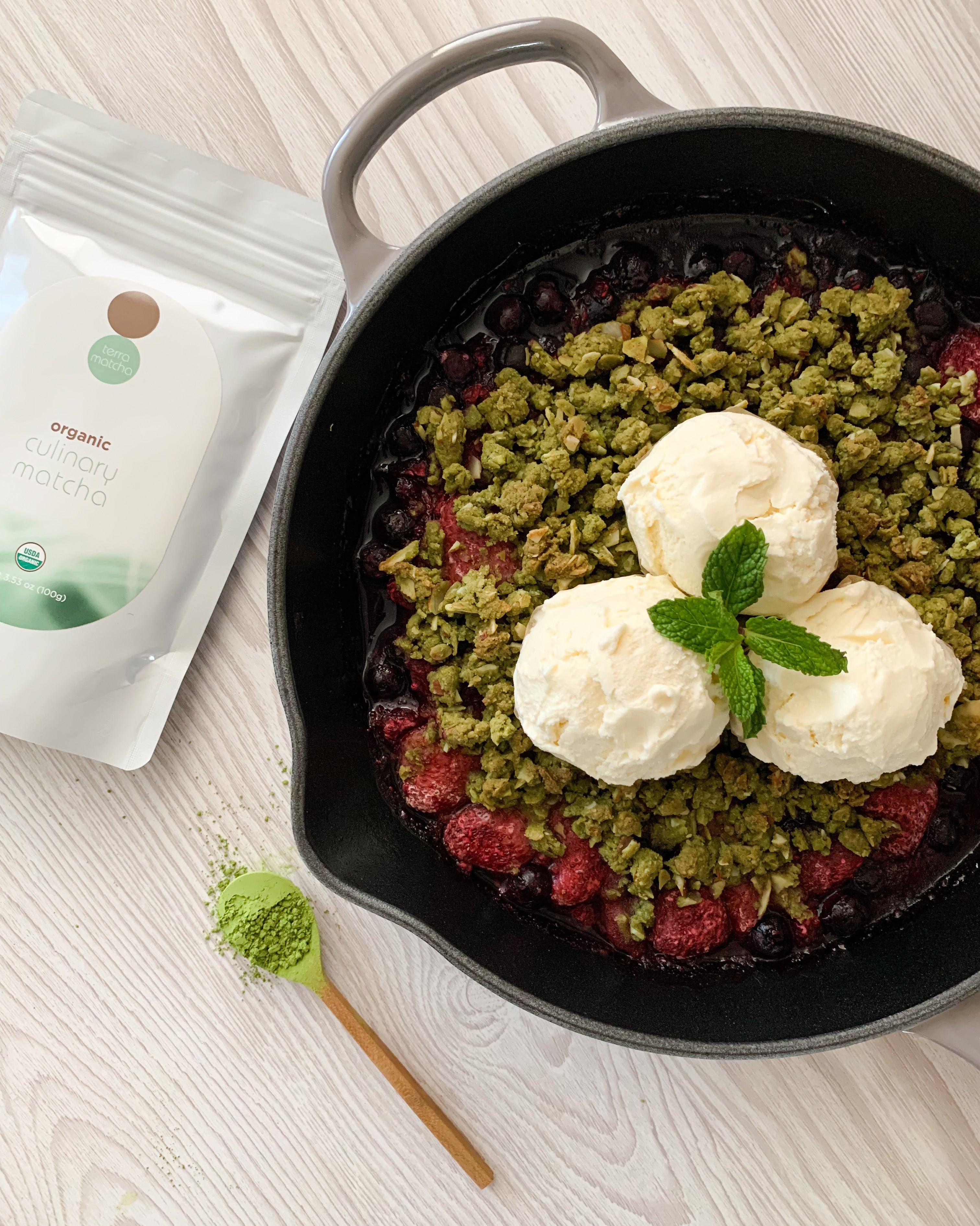 matcha-berry oat crumble in iron skillet and terra matcha culinary bag