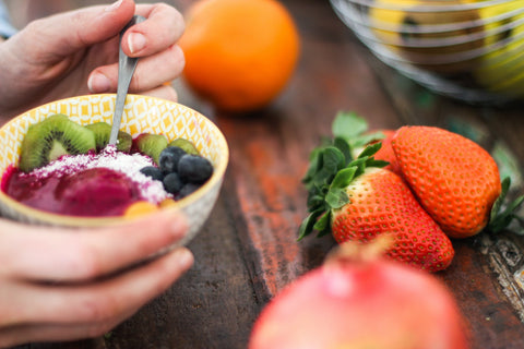 woman holding fruit salad - vitamin c foods - eating for healthier hair