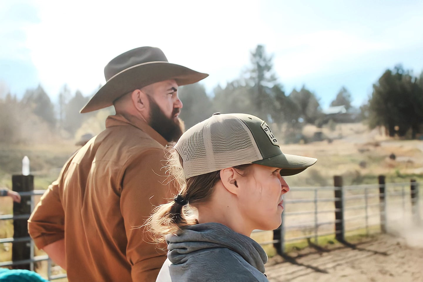 A man and a woman in hats looking into the distance on a sunny day.