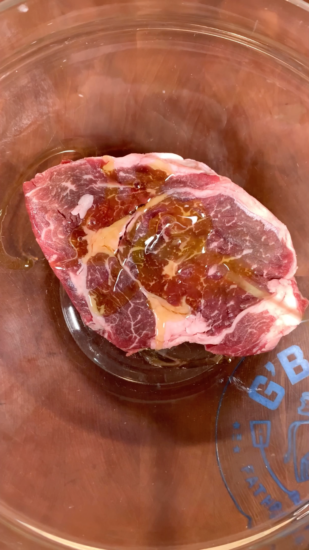 A well marbled certified ONYA ribeye steak in a glass bowl ready to be marinated before cooking
