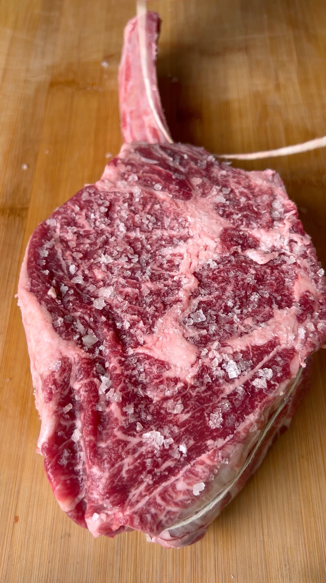 A huge certified ONYA tomahawk ribeye steak dry brined with sea salt hours before cooking.