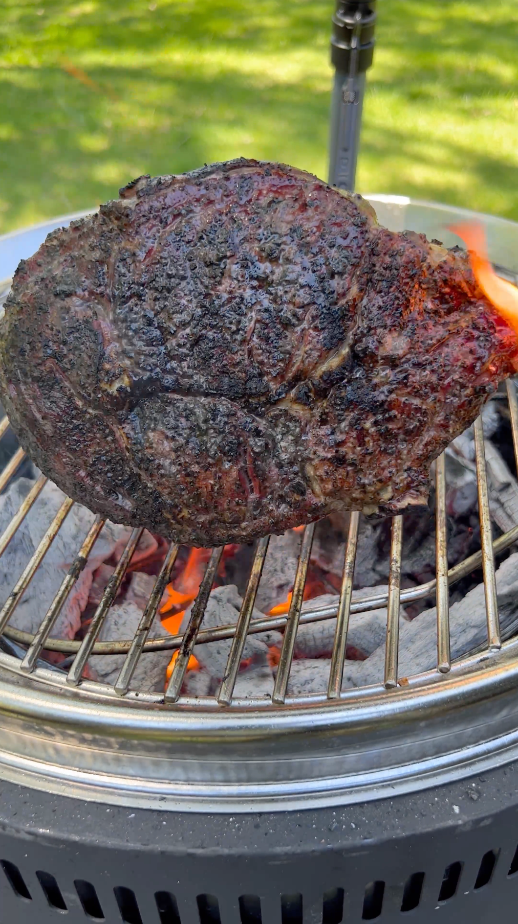 Beef tomahawk ribeye steak reverse seared over high heat open flame on Burch Barrel live fire charcoal grill