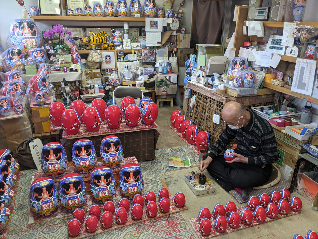 In his studio surrounded by countless handcrafted Daruma dolls, Mr. Hongo handpaints the details onto the dolls to create their signature design blue